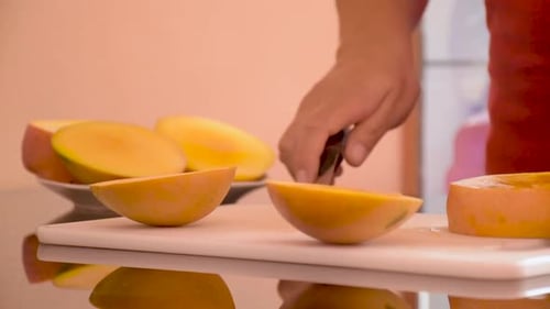 Close Up Of Hands Cutting A Ripe Mango
