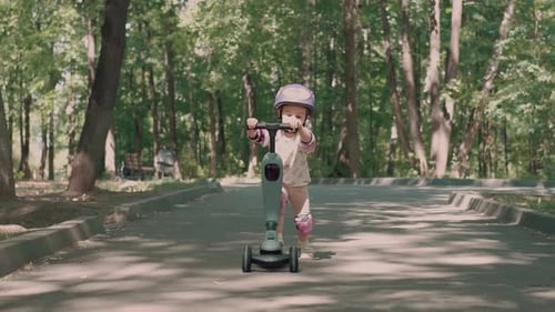 Girl Riding Scooter on Paved Path in Park