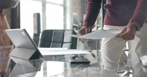 Midsection of african american casual businessman looking at documents in office, slow motion