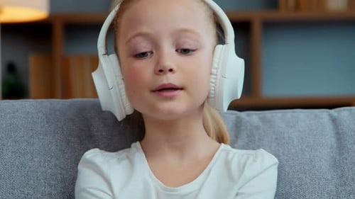 Blonde Girl Listening to Music with Headphones Indoors