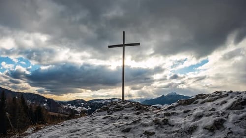 Stahlkreuz in verschneiter Natur bei Sonnenuntergang mit Dramatisch Wolken, religiöser Zeitraffer