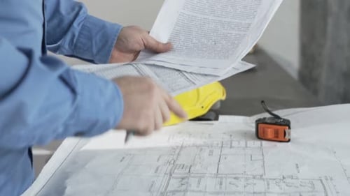 Mann überprüft Baupläne und Dokumente am Tisch der neuen Inneneinrichtung