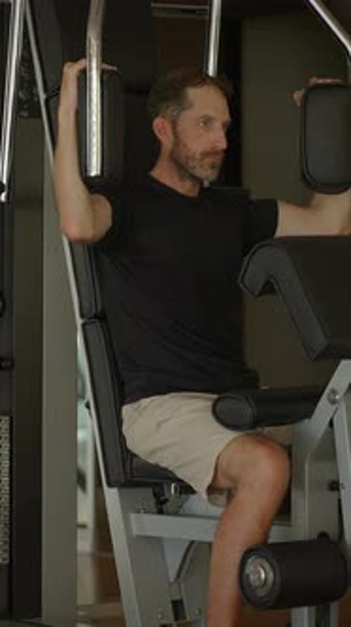 A Man is Actively Engaging in a Focused Exercise Routine at the Gym Using Strength Equipment