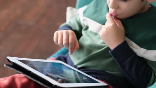 Boy Using Tablet Device While Sitting Indoors