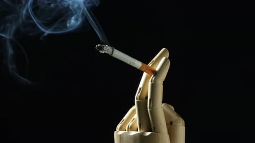 Wooden Robot Hand Holding Cigarette with Smoke on Black