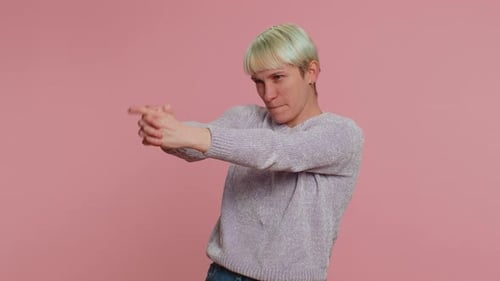 Frau zeigt mit Fingergewehr herum und sieht selbstbewusst aus, trifft Entscheidungen, Schießen, Töten