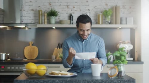 Excited Man Reading Letter in Bright Kitchen