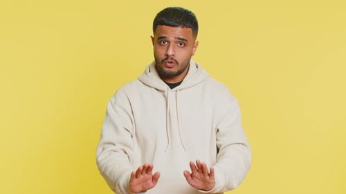 Young Adult Man Speaking and Gesturing on Yellow