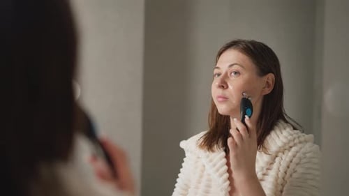 Female Does Microcurrent Procedure for Face Lift in Bathroom