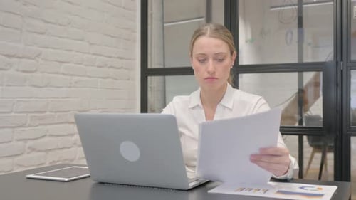 Woman Working with Laptop and Paperwork at Desk