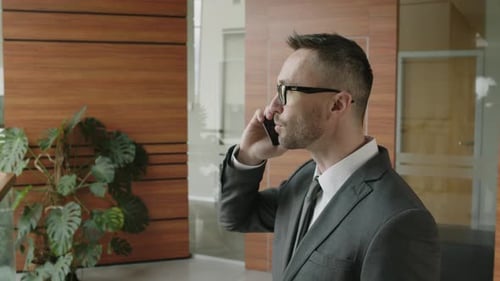Businessman Talking on Phone in Office Lobby