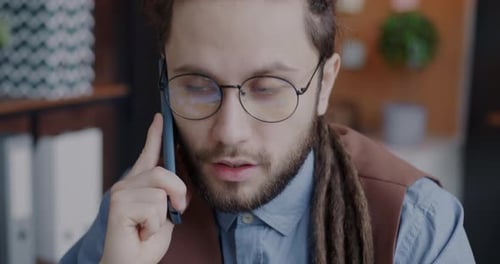 Young Man Office Worker Speaking on Mobile Phone Talking to Client Working Indoors in Office