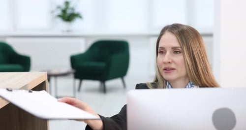 Receptionist working with guest at reception desk indoors