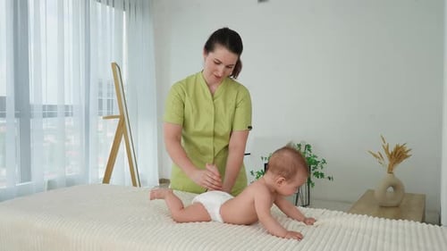 Side View of Adorable Little Infant Boy Getting Massage From Female Masseuse Massaging Newborn Baby