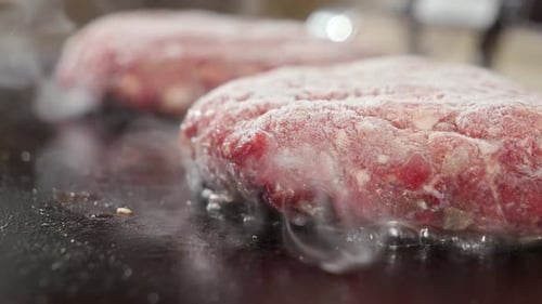 Closeup of cooking burgers on electric grill.