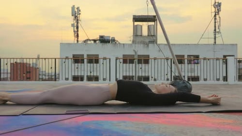 Woman Practices Yoga on Urban Rooftop at Sunset