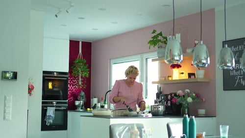 Mature woman preparing food in a pan on an electric stove in a contemporary kitchen