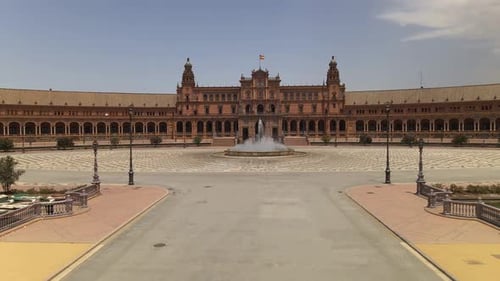 Avanza con la plataforma rodante detrás de la estatua hacia una gran plaza vacía con fuente en la Plaza de España, en Sevil