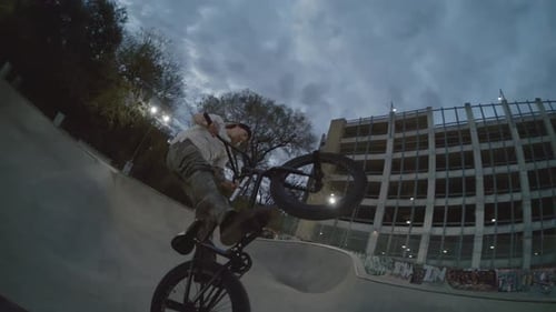 Bike wheel spinning in slow motion near camera during huge BMX air at skatepark out of pool bowl ram