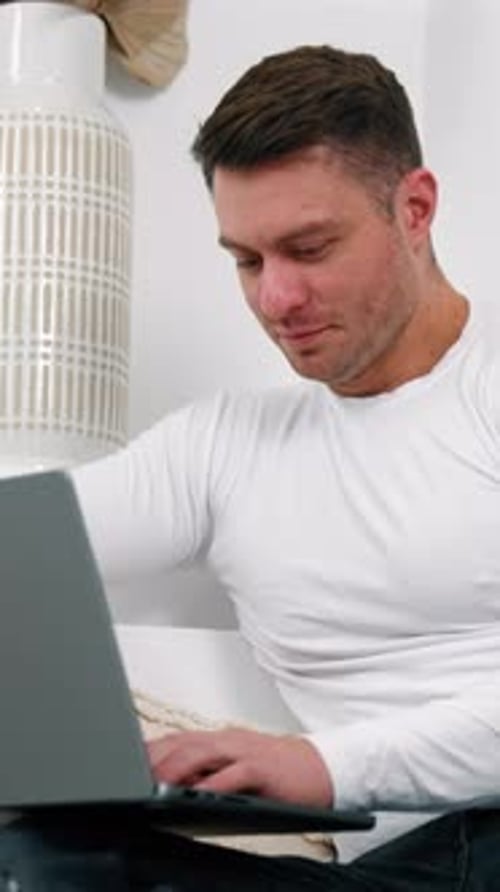 Man Using Laptop Device Indoors in Bright Home Setting