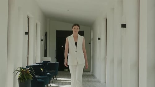 Stylish Model In White Trouser Suit Walks Through Hotel Lobby