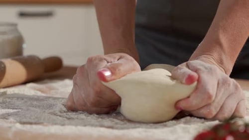 Hands Kneading Dough on Floured Kitchen Surface