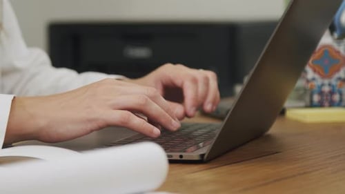 Doctor listening to patient and typing on a laptop computer keyboard inside her clinic