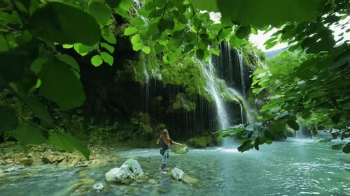 Happy woman tourist enjoying amazing waterfall .Female tourist admiring the waterfall in the forest.