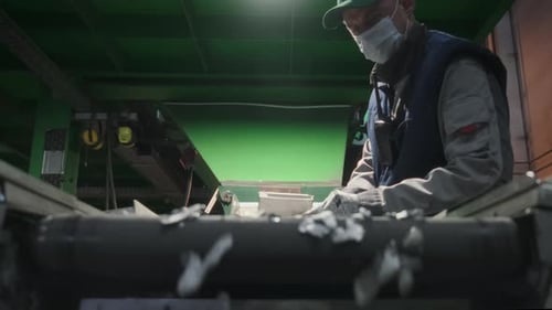 Worker Sorts Plastic on Conveyor Belt