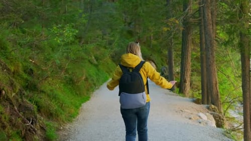 Tourist in Yellow Jacket Enjoying the Walk in Forest Path