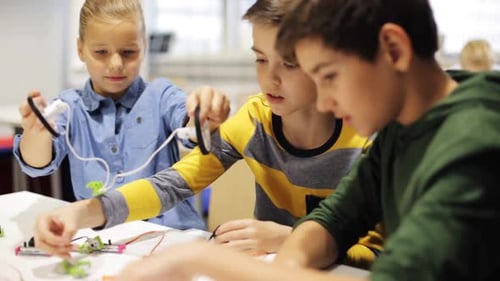 Smiling kids at robotics school learn to create robots together in science class
