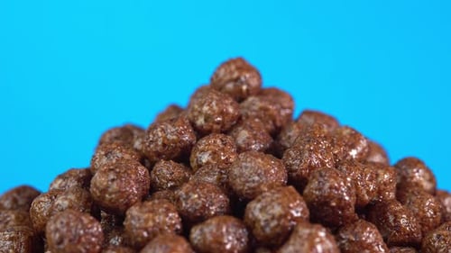 Chocolate cereals rotate on blue background. A healthy breakfast spinning in glass. Making cereals