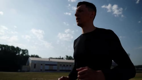 A Man in a Black Sports Uniform Runs Through the Stadium The Silhouette of an Athletic Man