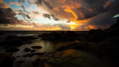 Epic sunset sunflare with dramatic colorful clouds over ocean, coastal timelapse