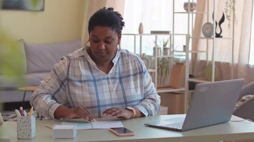 Woman Typing and Writing at Desk in Home Office
