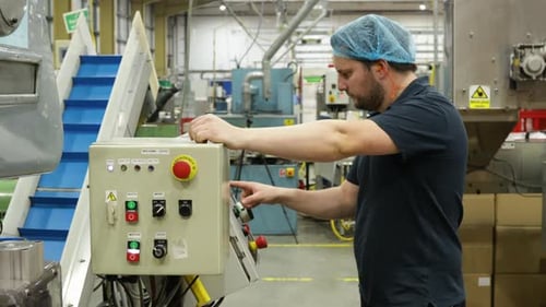 Male warehouse factory worker presses buttons on a control panel in operating center