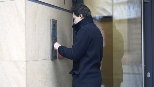 Teenage boy inputs intercom code to enter modern apartment building