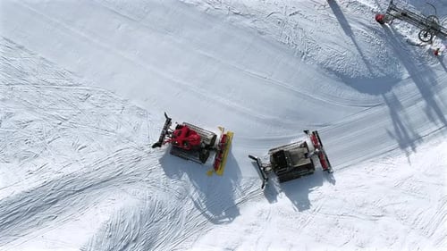 Snow Groomer and Piste Basher Working on a Ski Piste Aerial View