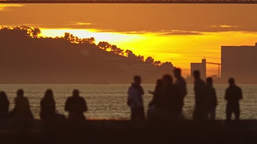 Coucher de soleil, un groupe de personnes debout ensemble près d'un pont