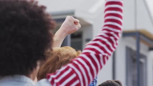 Back view of diverse group of protesters with raised hands screaming
