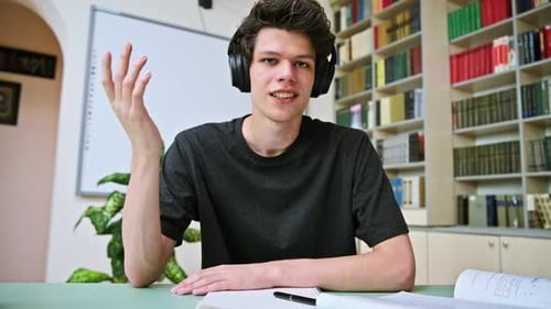 Web Cam Portrait of College Student Guy in Headphones Looking Talking to Camera