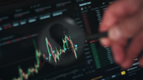 Magnifying Glass Examining Stock Market Data on Screen