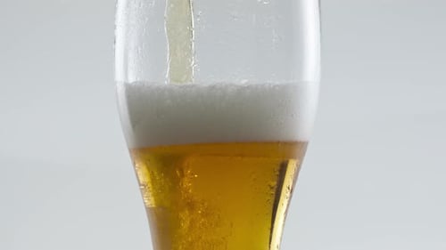 Beer Pouring into Glass with Head and Condensation