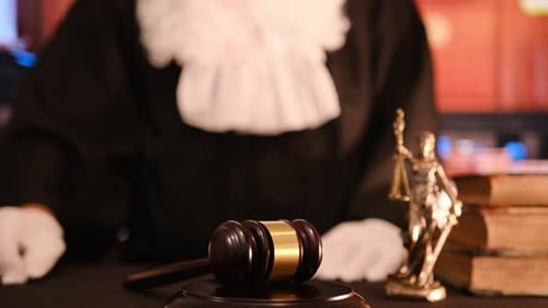 Judge with Gavel and Justice Statue at Desk