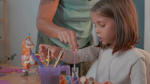 Child Painting Ceramic Figurines with Mom in Cozy Home