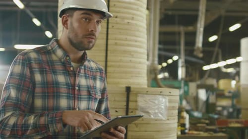 Der Arbeiter benutzt einen Tablet-Computer im Lager der Holzfabrik.