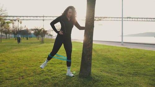 Athletic Woman Exercising with Resistance Band Outdoors