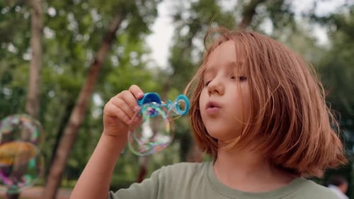 portrait beautiful cute little girl blowing soap bubbles in city park happy carefree childhood