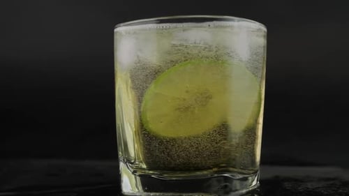 Shot of golden Mexican tequila with lime and salt on black background.