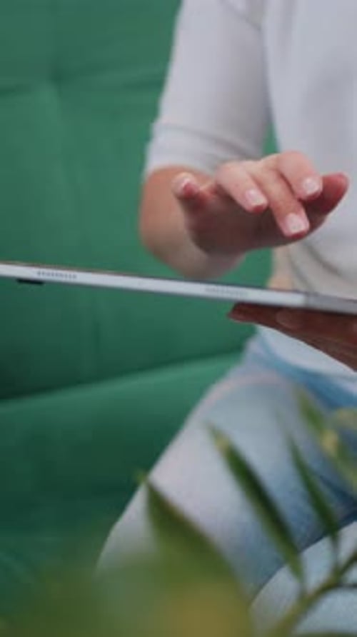 Woman Interacts with Tablet Device While Seated Indoors